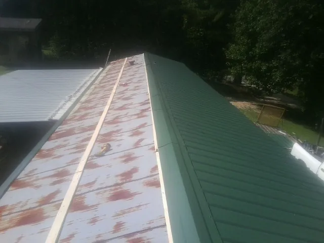 Old rusted panels beside newly installed green metal roofing — Wind Damage Roof Repair by Roofing Brothers in Kirkwood
