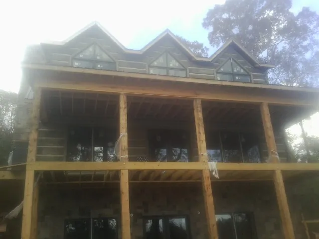 Dormers and porch framing on a large log home under construction — Roof Coating work by our crew in Kirkwood